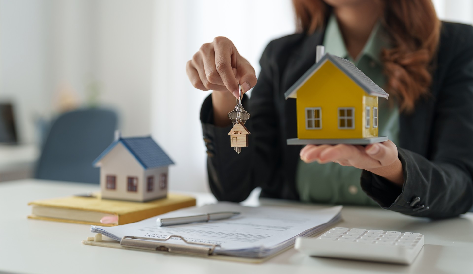 Asian real estate agent holding house key to his client after signing contract,concept for real estate, moving home or renting property